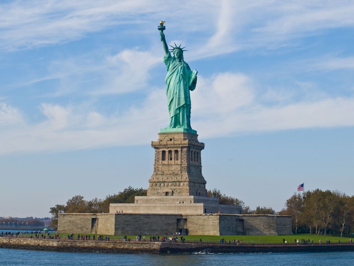 The Statue of Liberty on Liberty Island in New York Harbor under a bright blue sky