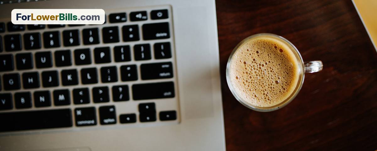Coffee cup next to an open laptop on a wooden table