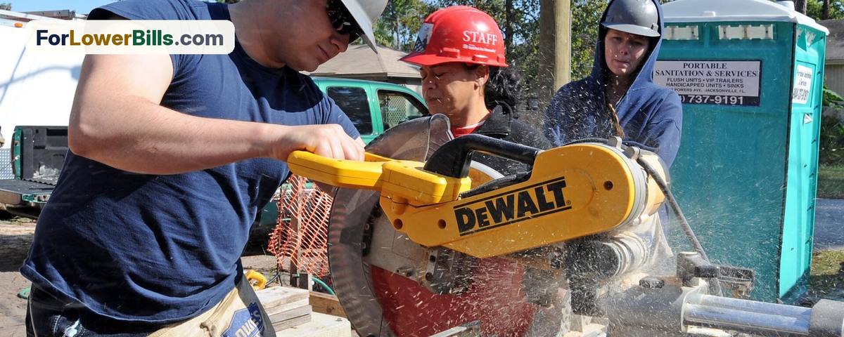Volunteers in hard hats cutting lumber at a Habitat for Humanity home build