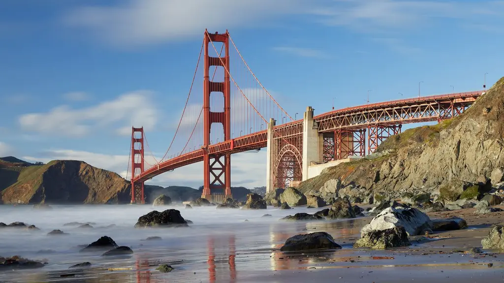 The red-orange Golden Gate Bridge seen from rocky Marshall's Beach at golden hour